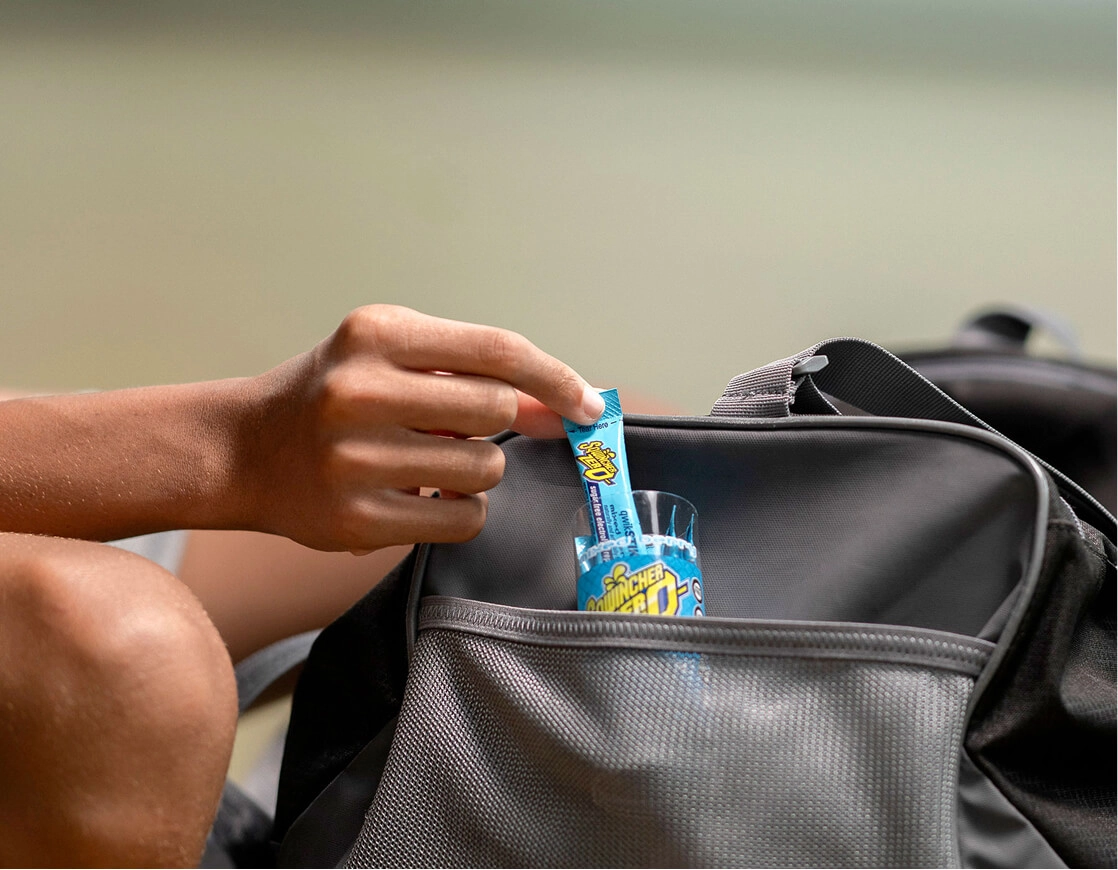 A hand pulling a package of Sqwincher out of a gym bag